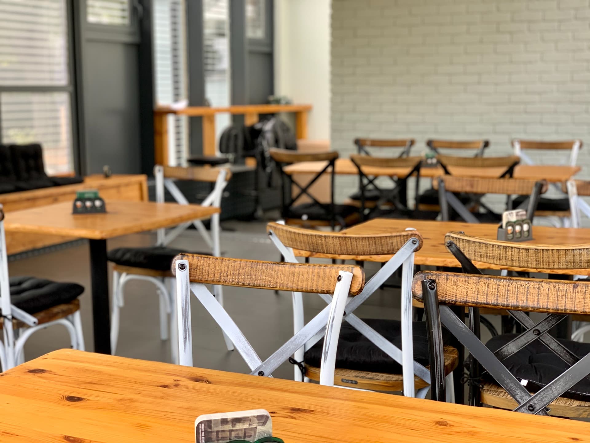Interiér Hostavického Vidláka — rustikální dřevěné stoly a židle u prosklené stěny